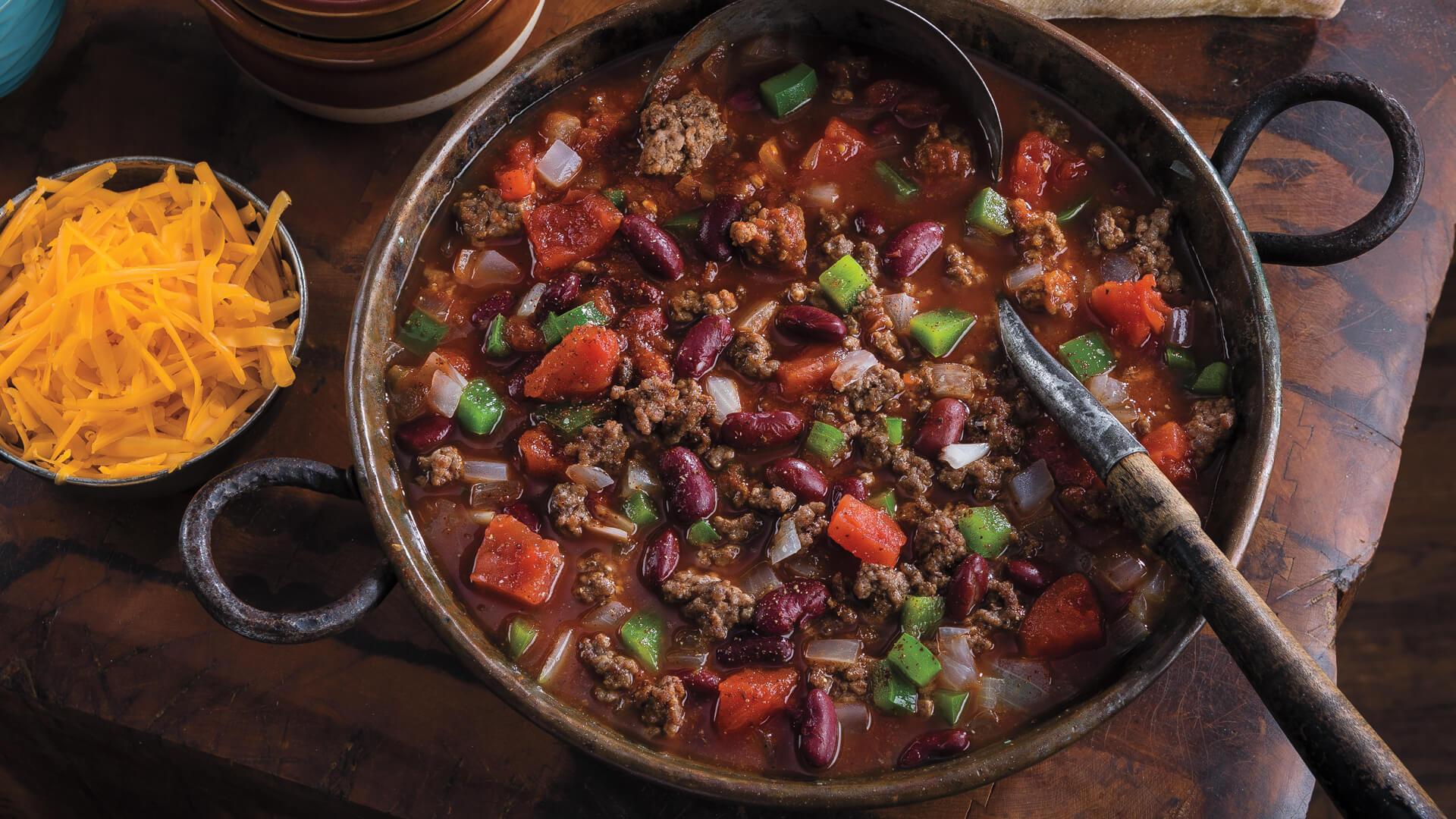 Rustic wooden table with a plate of chili-roasted beef cubes, steam rising, cozy lighting