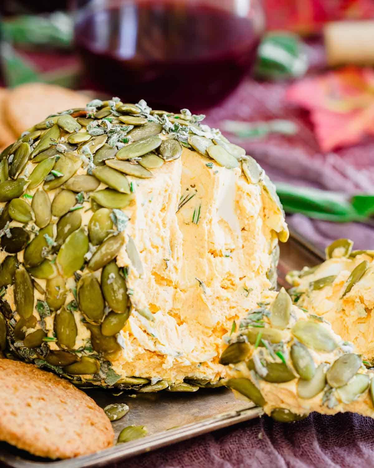 Close-up of a cheese ball mixture being blended in a stand mixer, showing the creamy texture and flecks of green herbs.