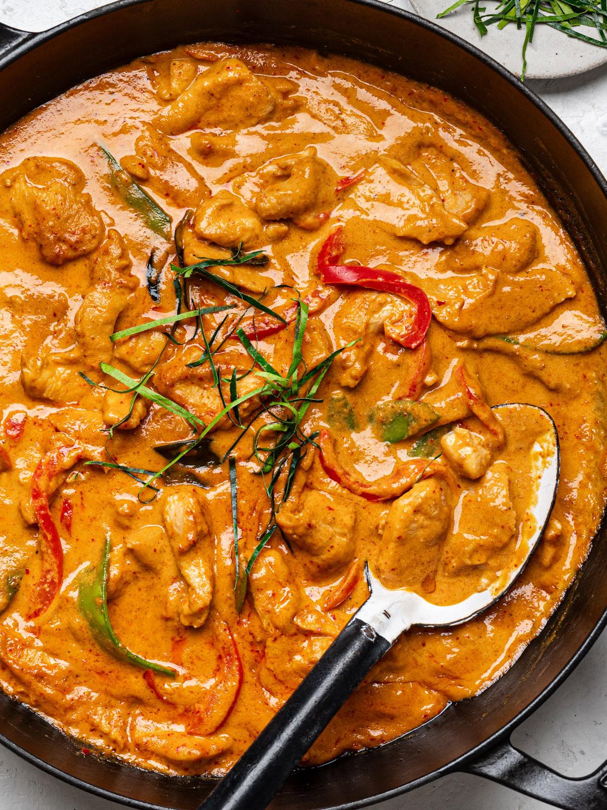 Close-up shot of ingredients for Panang curry: chicken, vegetables, coconut milk, and curry paste