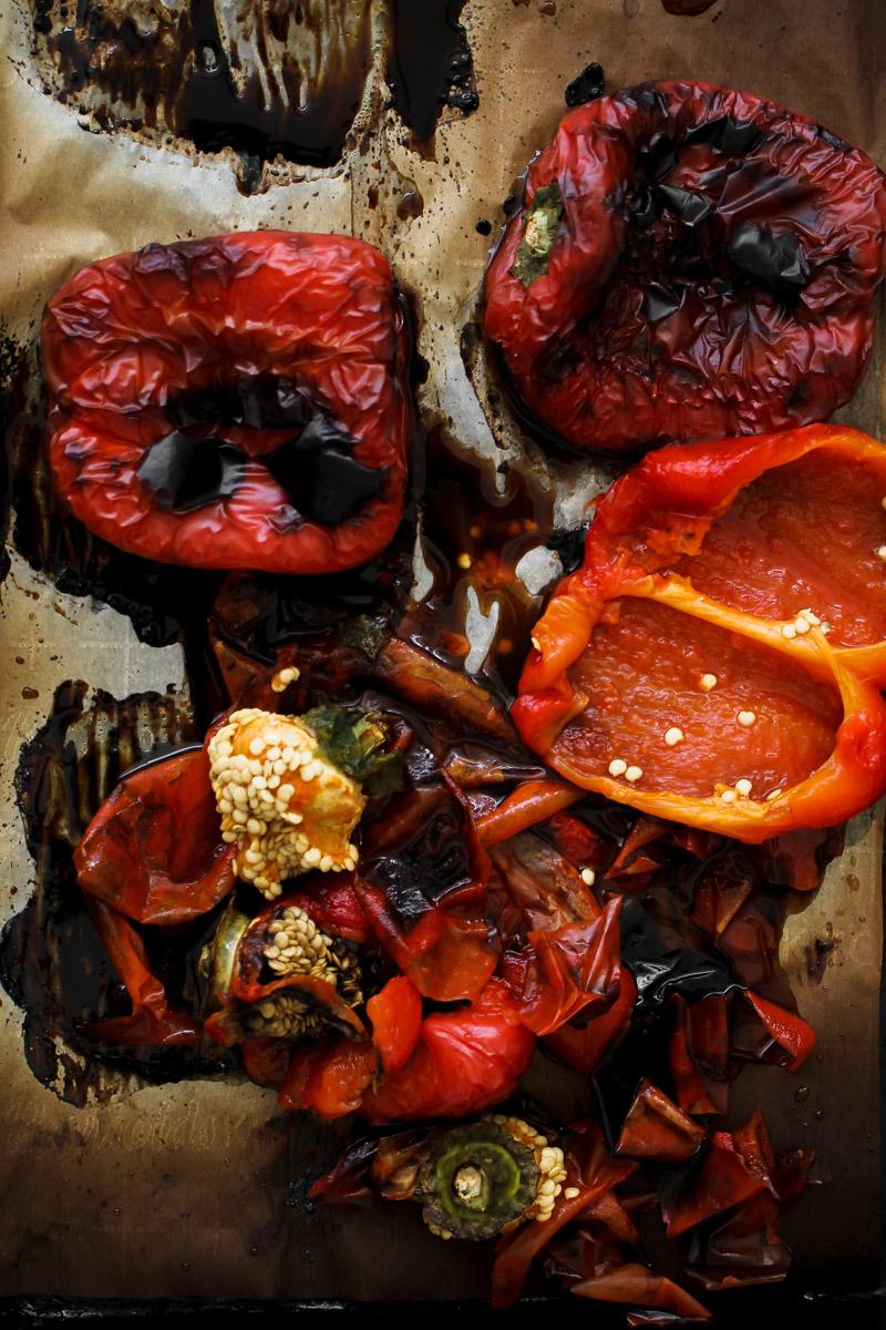brightly colored roasted red peppers and tomatoes on a baking sheet, slightly charred