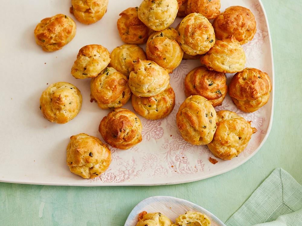 platter of savory cheese puffs with chives and a small bowl of mustard dip
