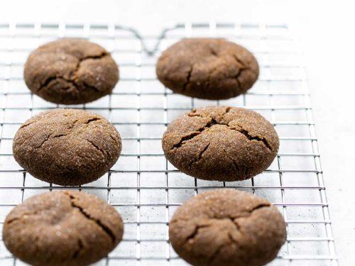 molasses cookies cooling on a wire rack, steam rising from a cup of tea