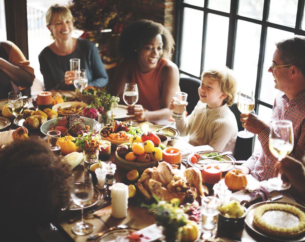 family laughing and eating soup at a Thanksgiving table