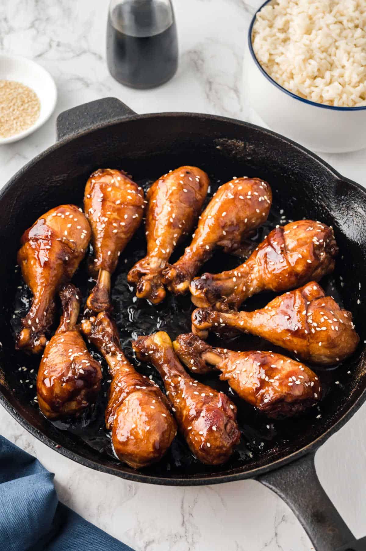 chicken pieces being tossed in sticky sauce in a pan
