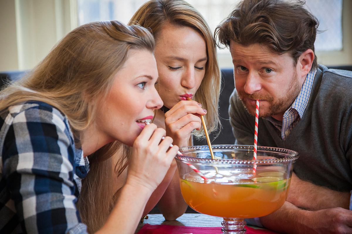 A person pouring hot orange clove punch into a glass from a large punch bowl.