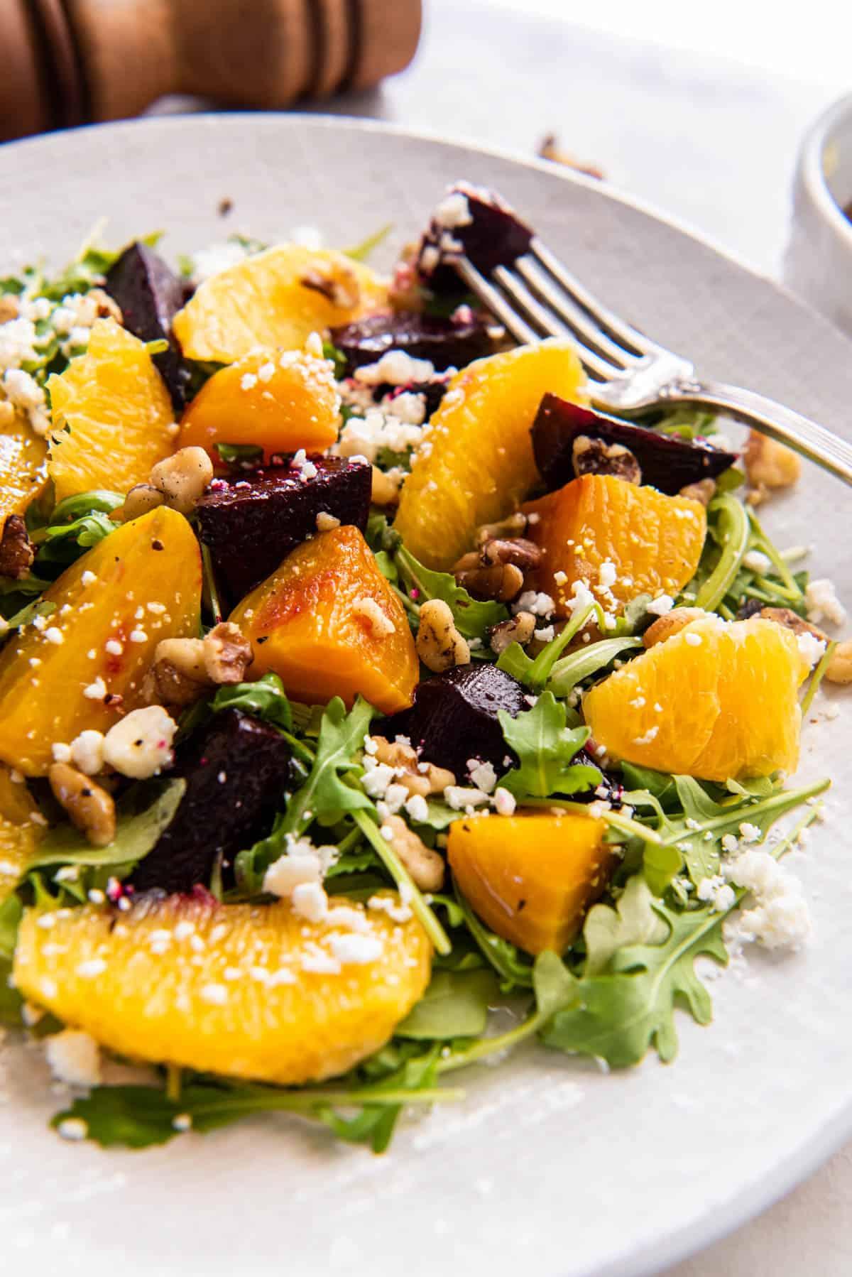 Close-up of a vibrant roasted beet salad with goat cheese, walnuts, and oranges