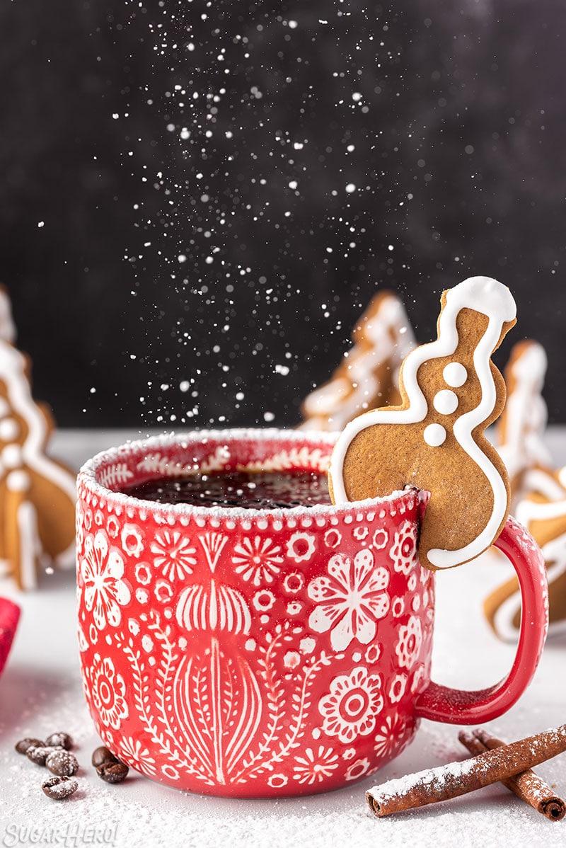 A plate of perfectly iced ginger cookies with a cup of tea, festive background