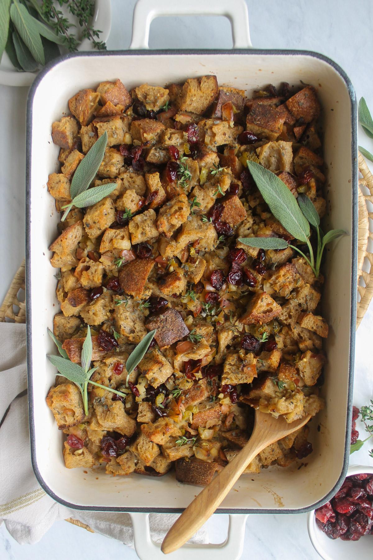 Thanksgiving maple cranberry stuffing in a rustic serving dish, garnished with fresh sage and cranberries