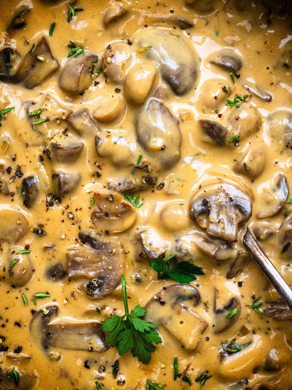 Close-up of a creamy mushroom sauce simmering in a skillet, with sliced mushrooms and garlic visible