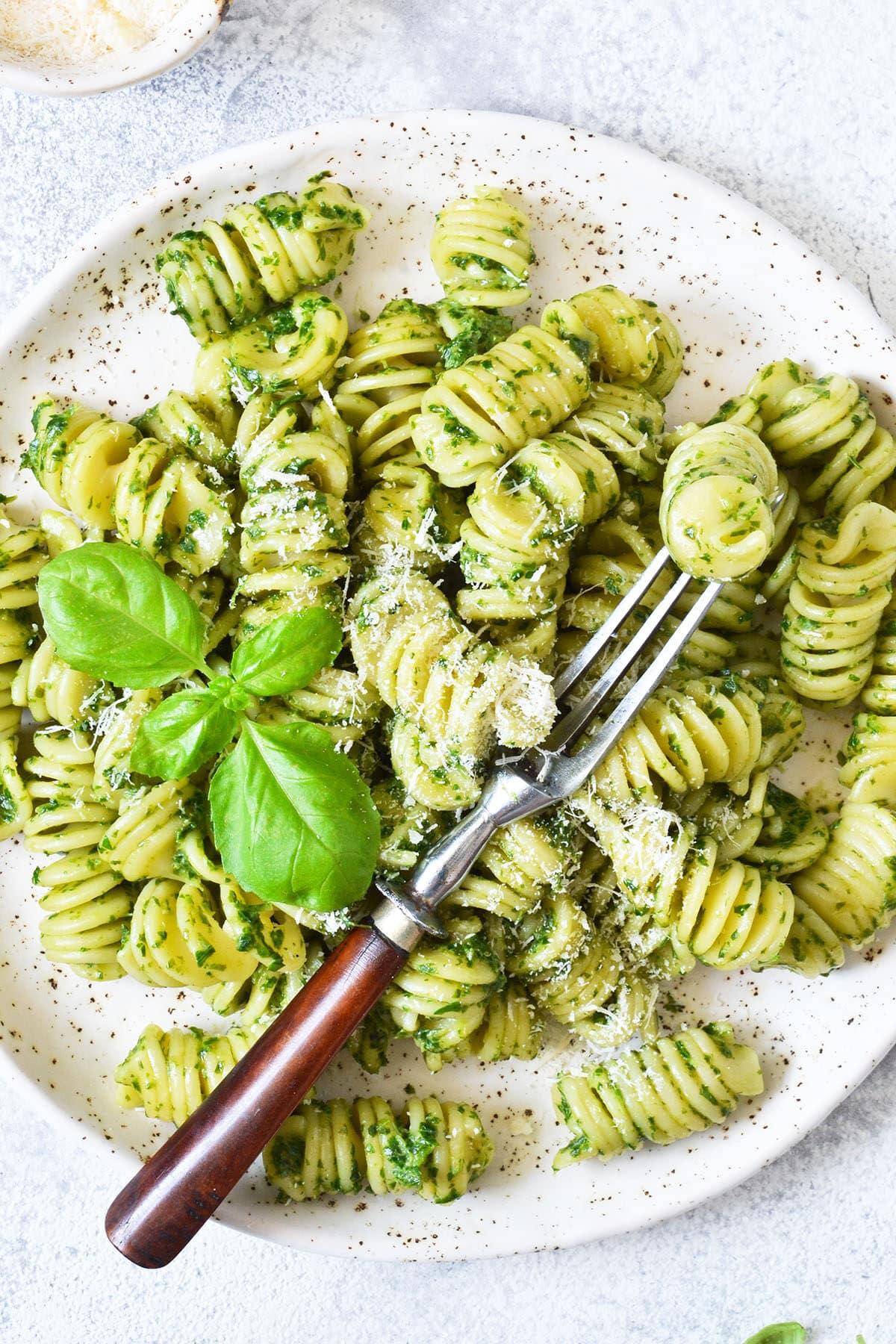 pesto parmesan mac and cheese plated and garnished with fresh basil leaves