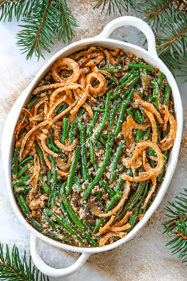 Homemade green bean casserole with golden buttery crumb topping, served on a rustic wooden table with holiday decorations