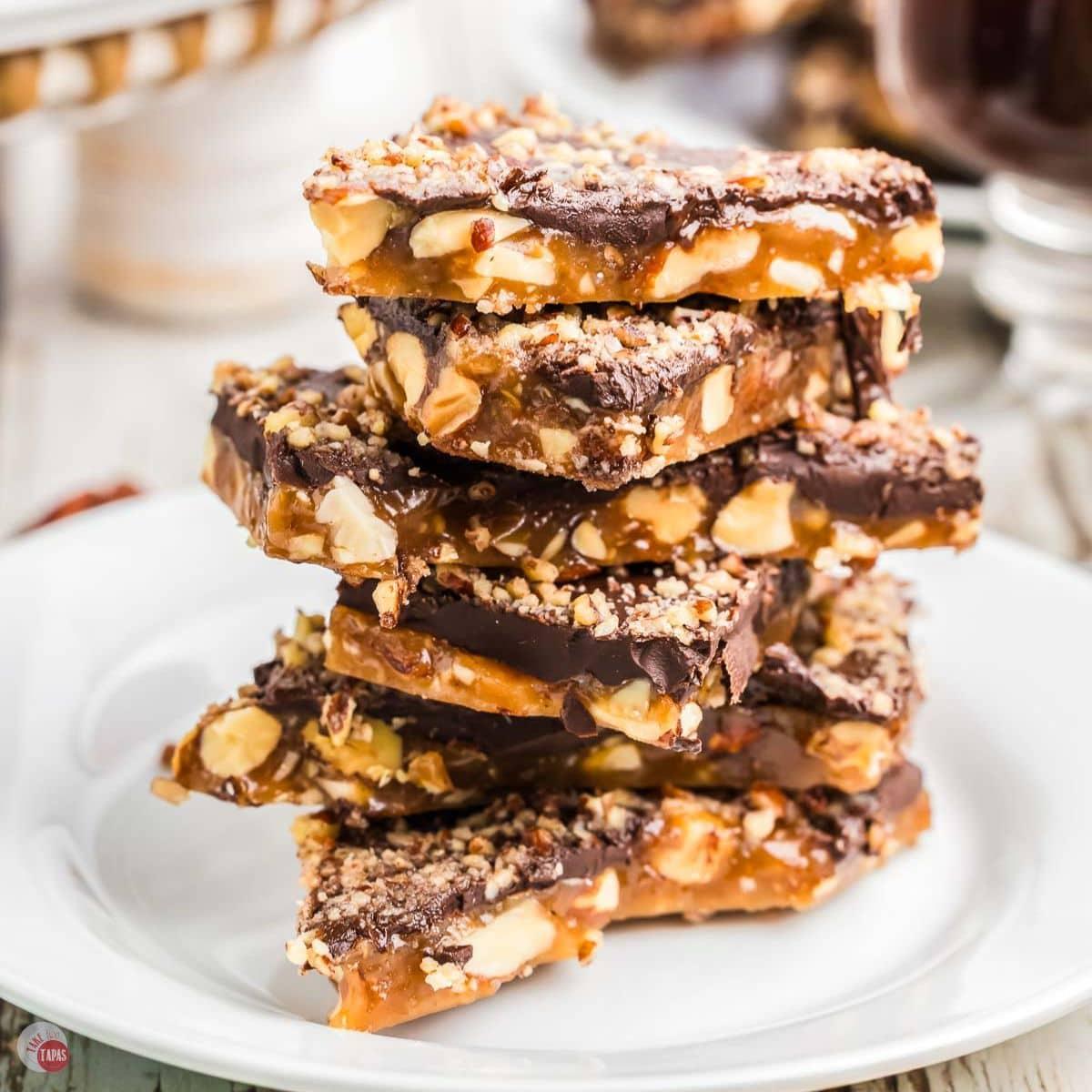 Assortment of homemade almond toffee pieces stacked beautifully, some with chocolate and sea salt