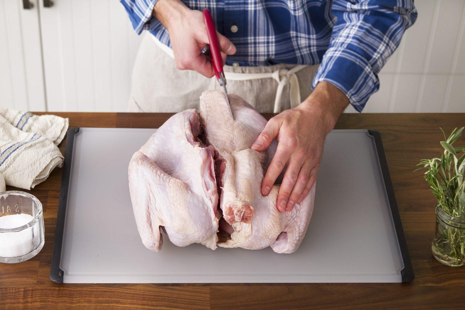 Person carefully seasoning a large turkey before roasting, showing hands and turkey.