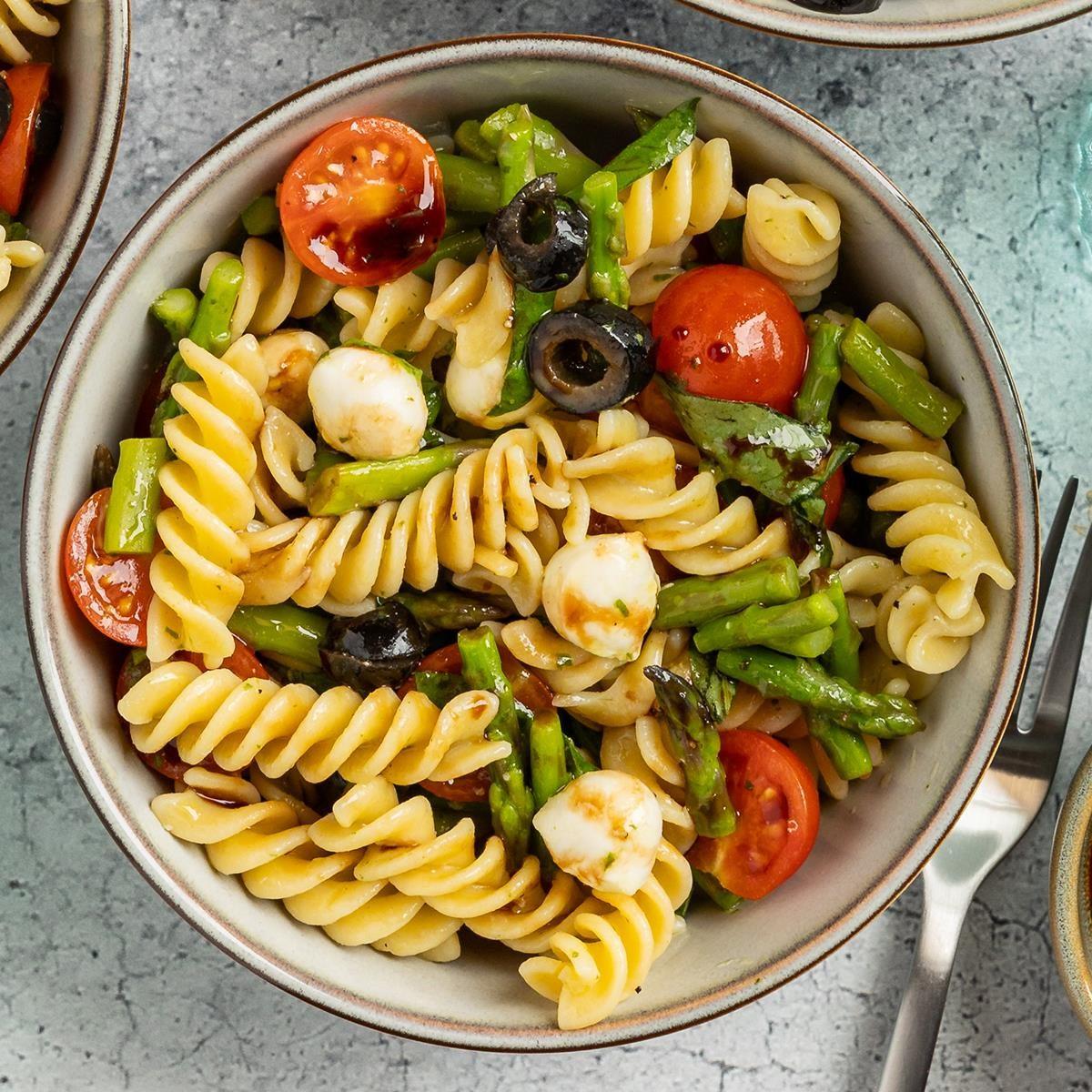 person enjoying a delicious bowl of gluten-free pasta salad outdoors