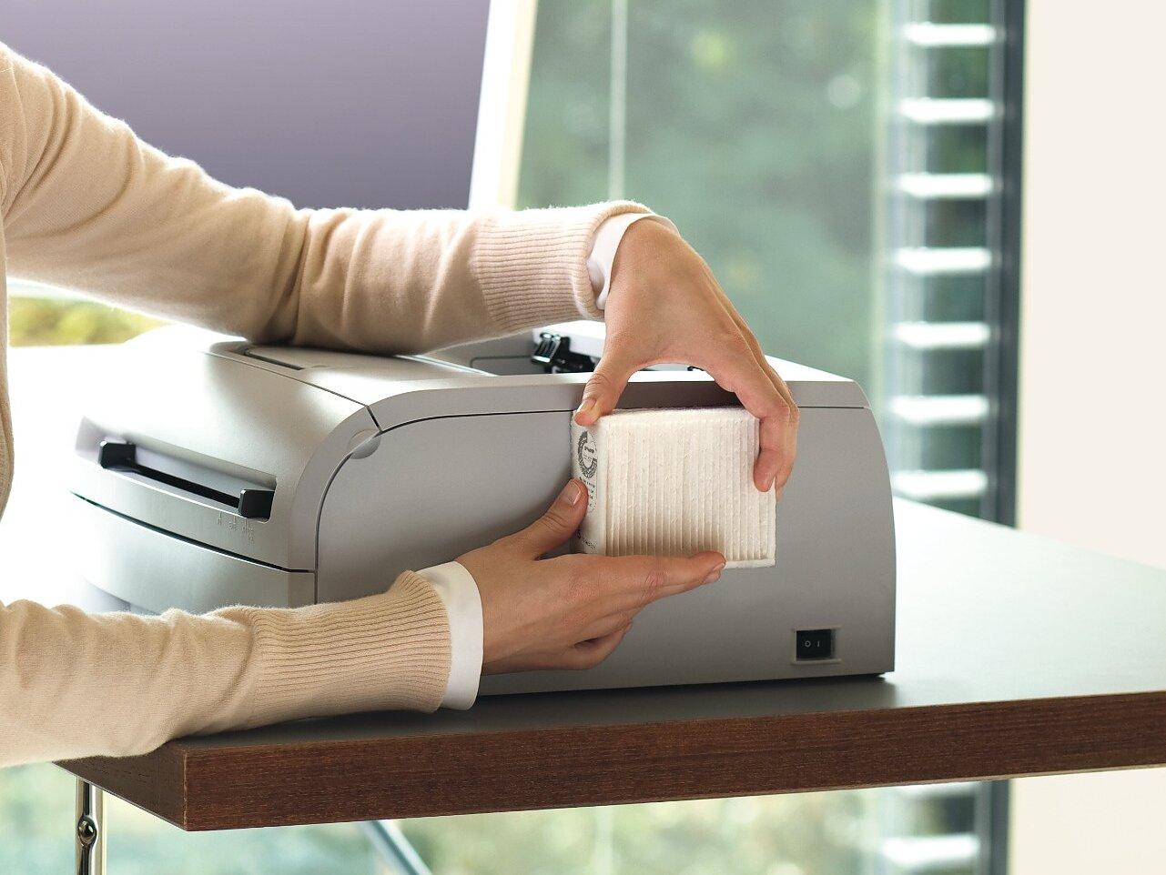 person cleaning a desk with a tape dispenser on it