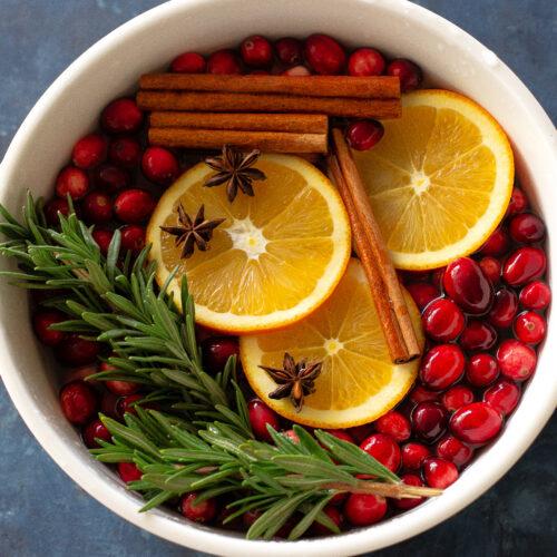 fresh cranberries simmering gently in a saucepan with orange zest and cinnamon sticks