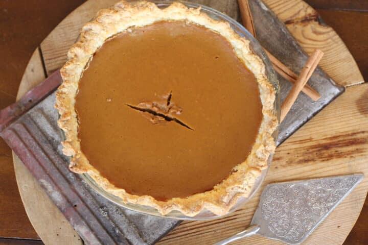 Whole pumpkin pie on a cooling rack, steam gently rising