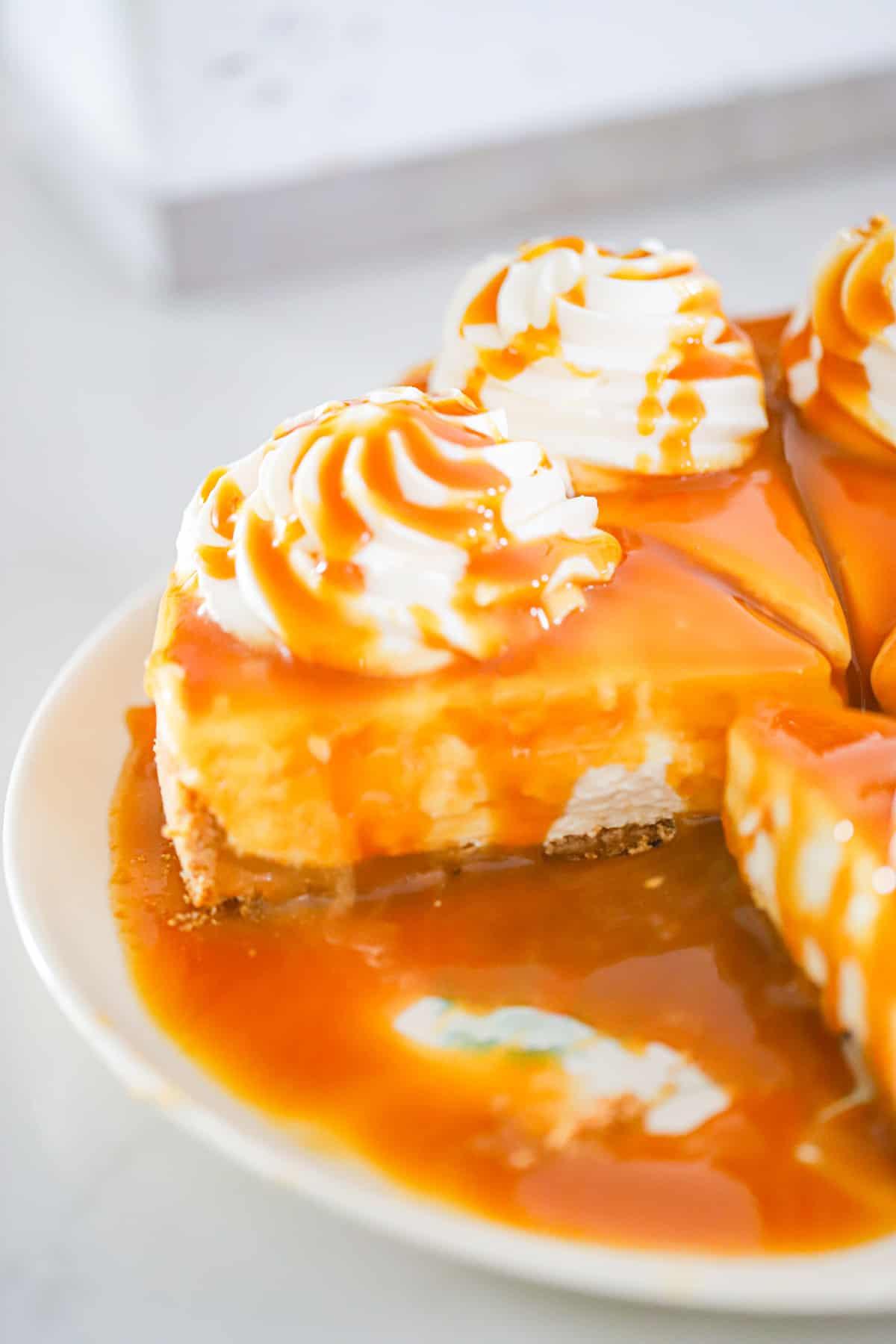 Caramel cheesecake being garnished with whipped cream and a sprinkle of sea salt