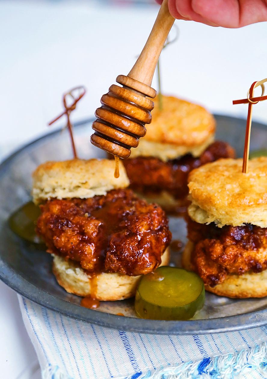 Drizzling hot honey sauce over a fried chicken biscuit sandwich