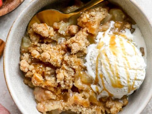 Close-up of molten apple crisp crumble served in a bowl with melting vanilla ice cream