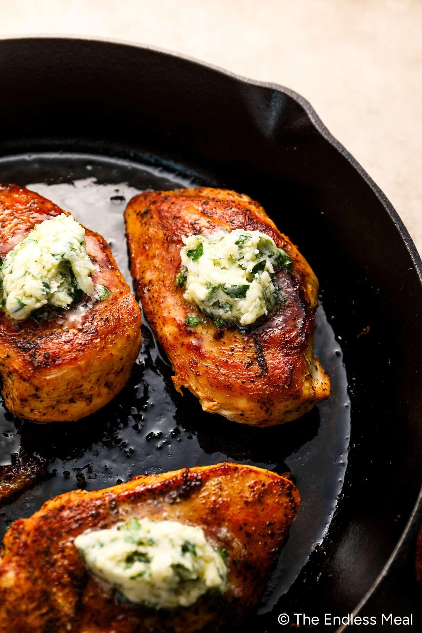 Woman happily cooking golden chicken breast in a cast iron skillet