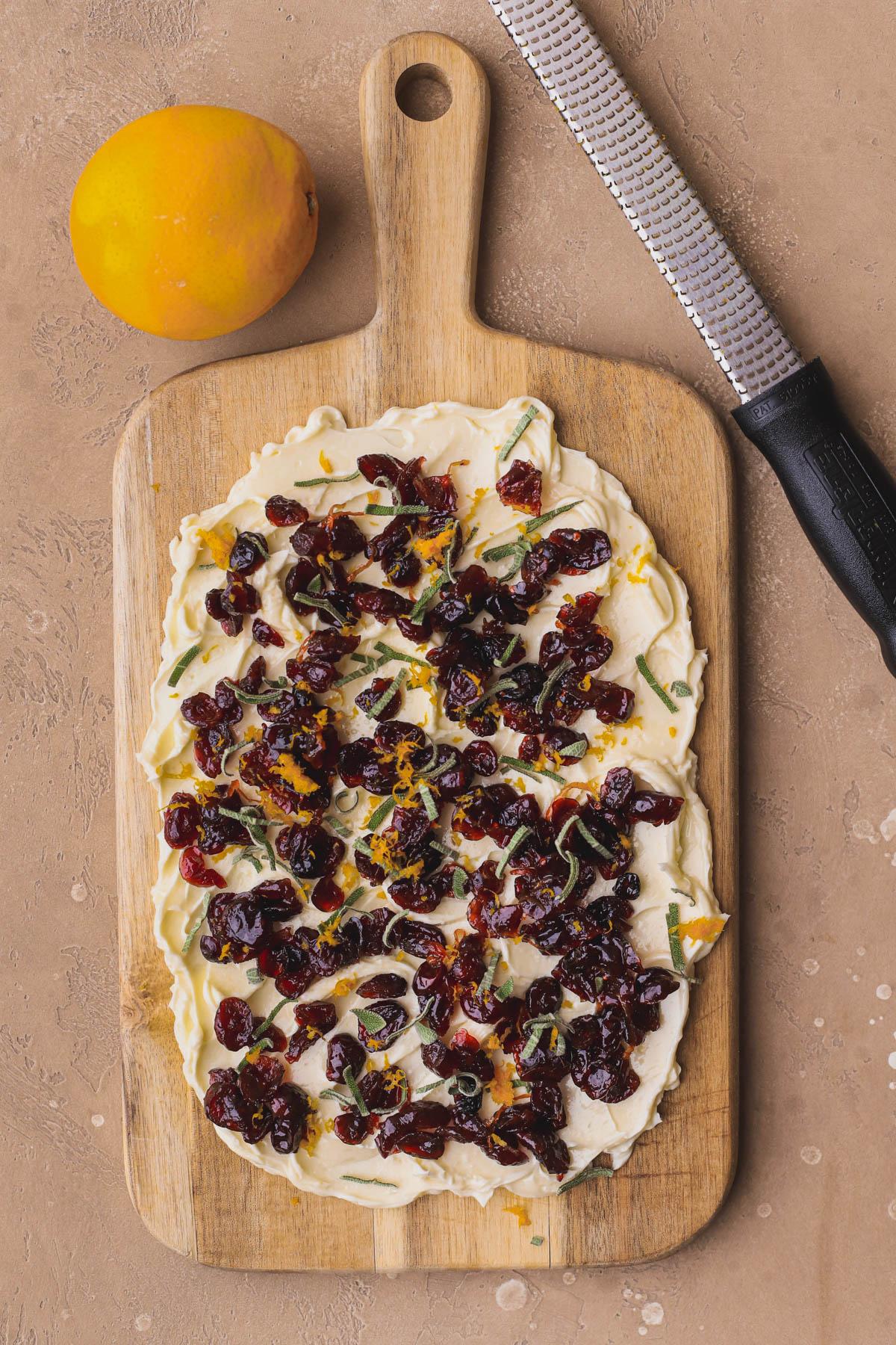 Close-up of fresh cranberries, orange zest, and honey on a wooden cutting board