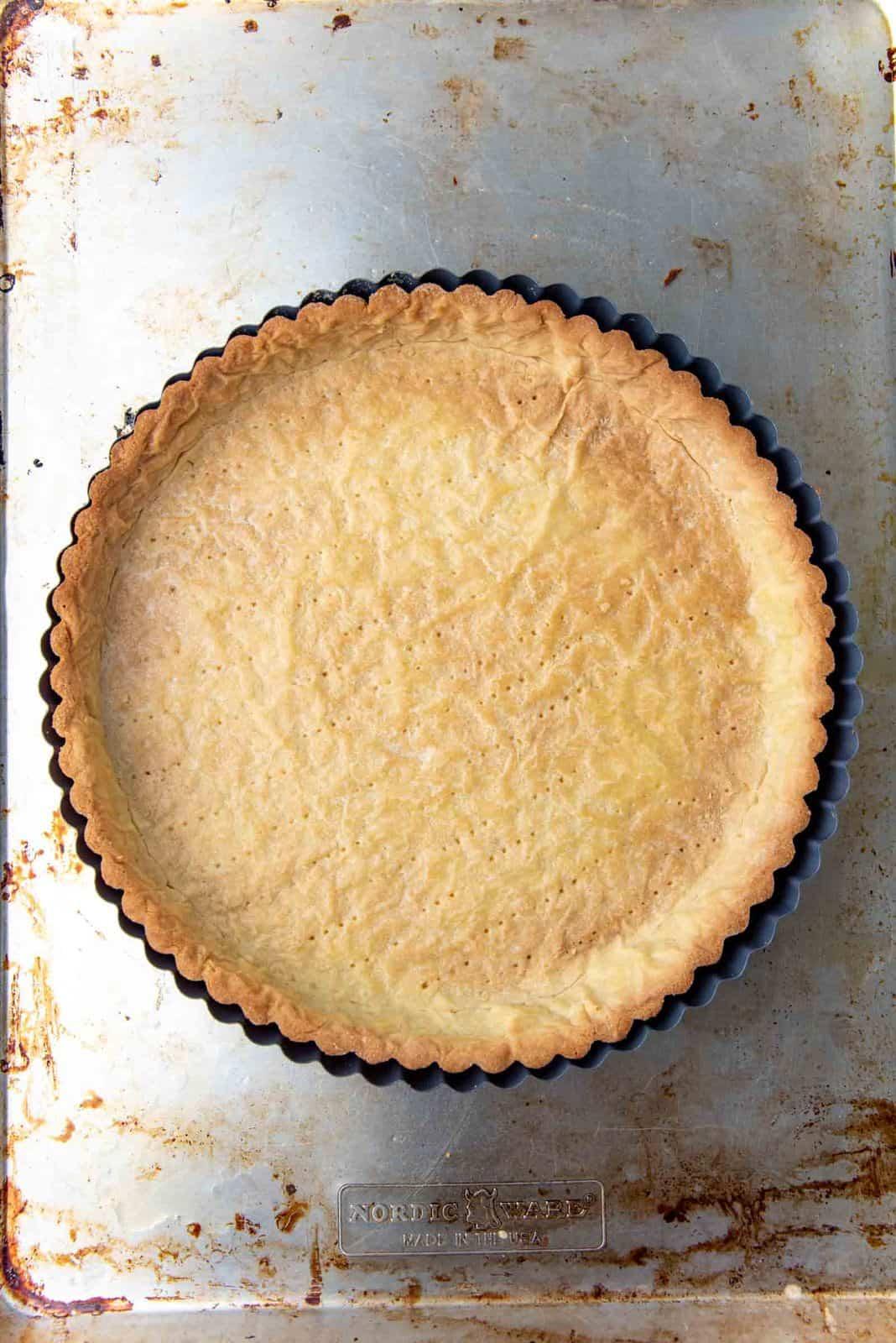 Close-up of golden brown shortcrust pastry in a tart pan, cooling on a wire rack