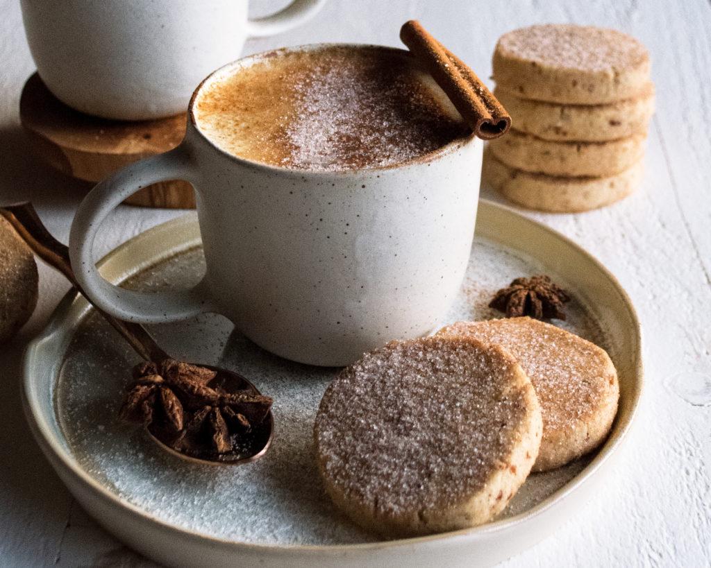 person enjoying an espresso shortbread cookie with a latte at a cozy coffee shop, autumn theme