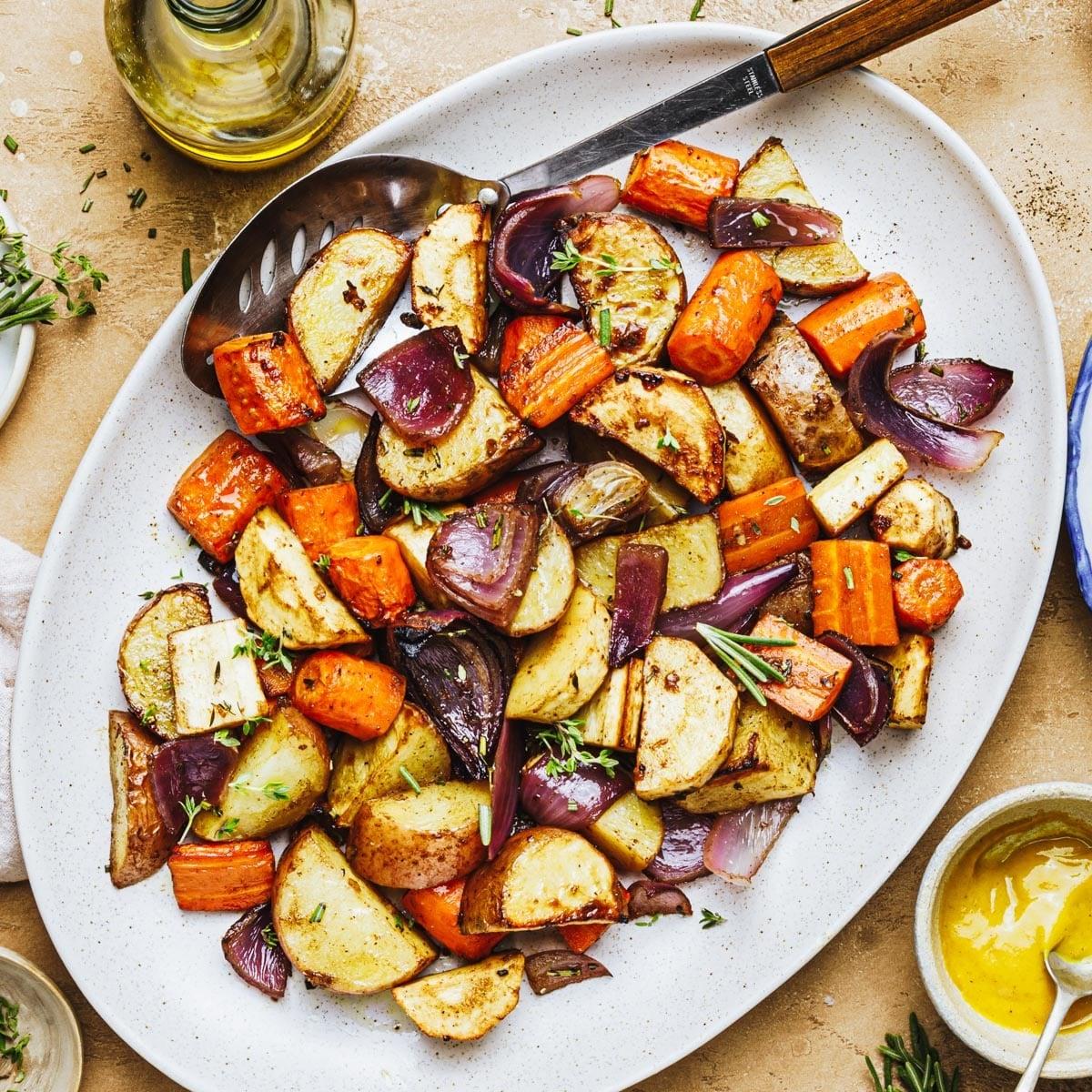 overhead shot of a large sheet pan filled with roasted root vegetables, glistening with oil