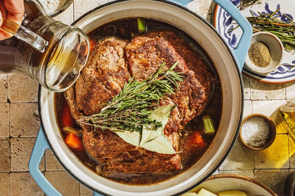 hearty chili-pepper beef roast in a Dutch oven, rustic kitchen