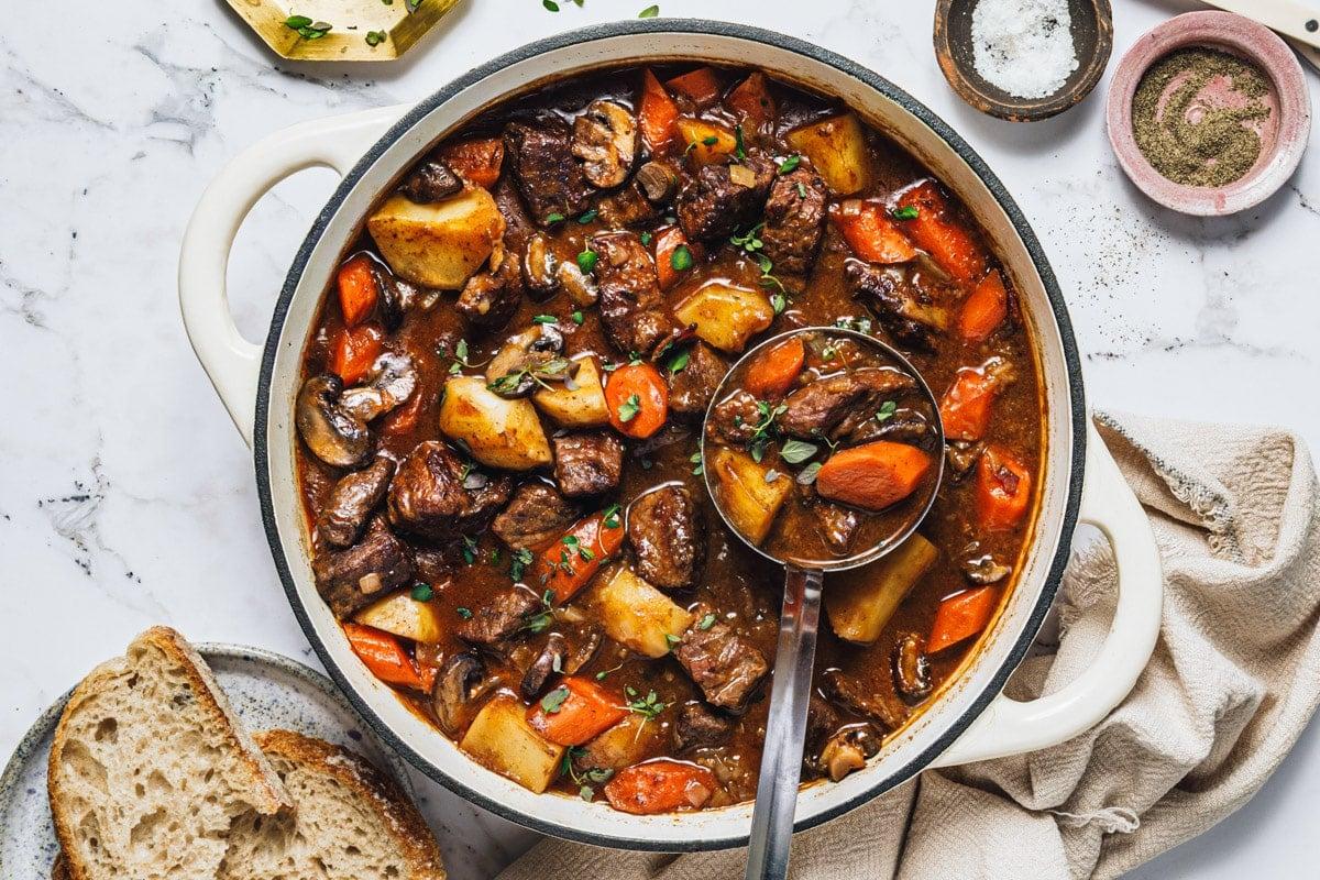 Rustic beef pasta stew in a Dutch oven with crusty bread