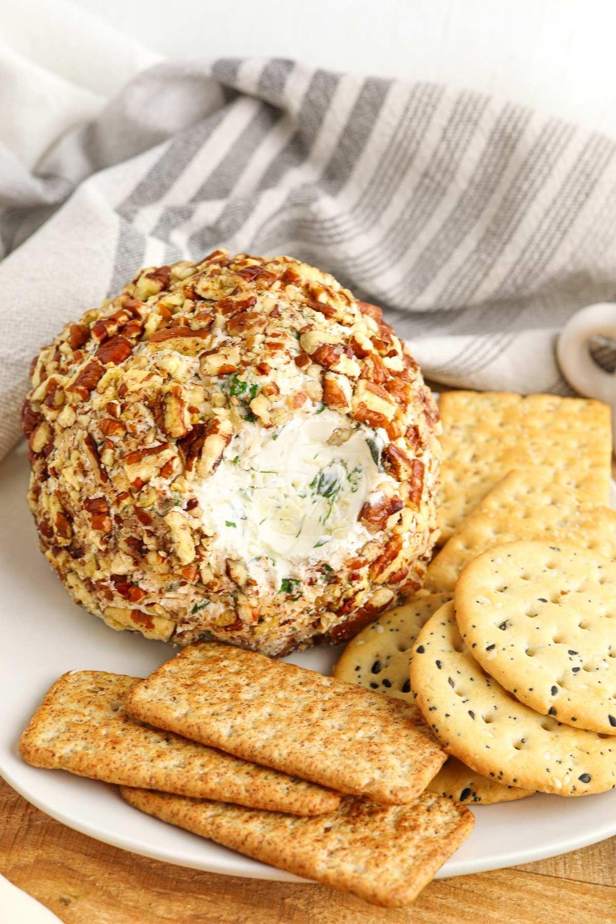 Delicious herbed cheese ball with pecans and crackers on a rustic wooden board, perfect party appetizer