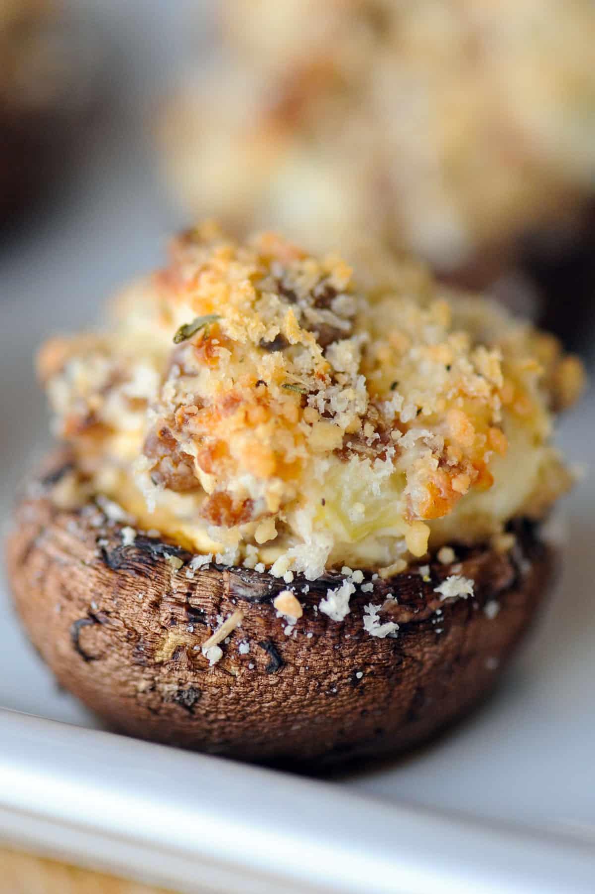 Close-up of golden brown sausage stuffed mushrooms with fresh herbs on top
