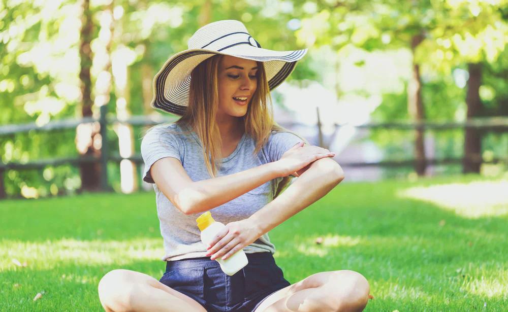 woman applying sunscreen in a park in spring