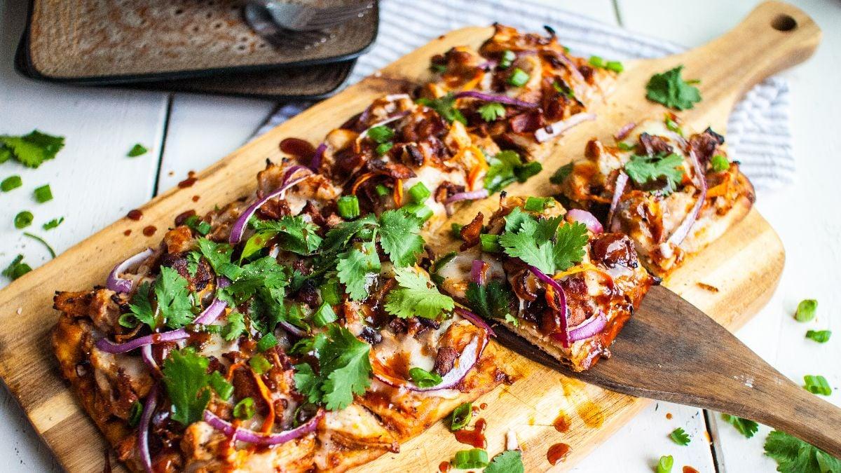 A family enjoying BBQ chicken flatbread together outdoors