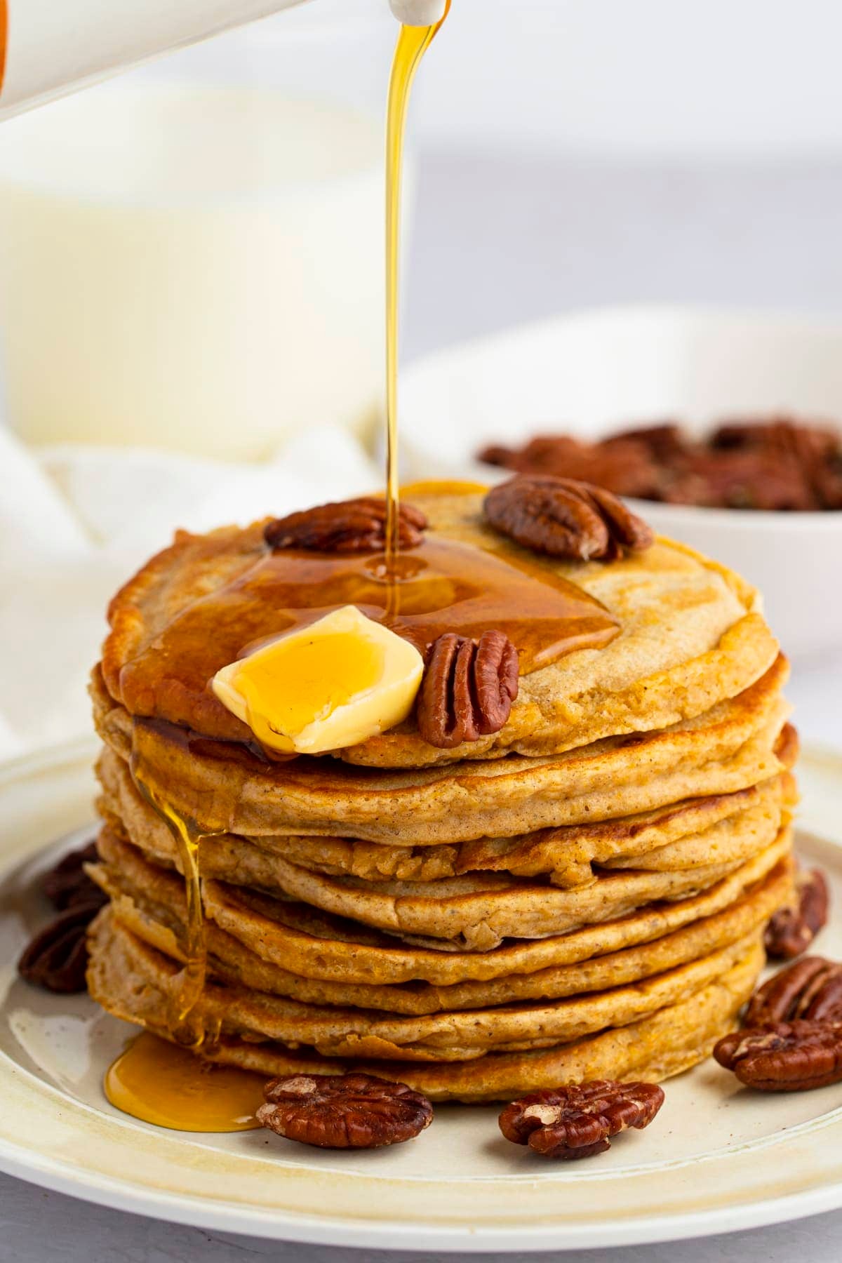 stack of sweet potato cottage cheese protein pancakes topped with pecans and maple syrup