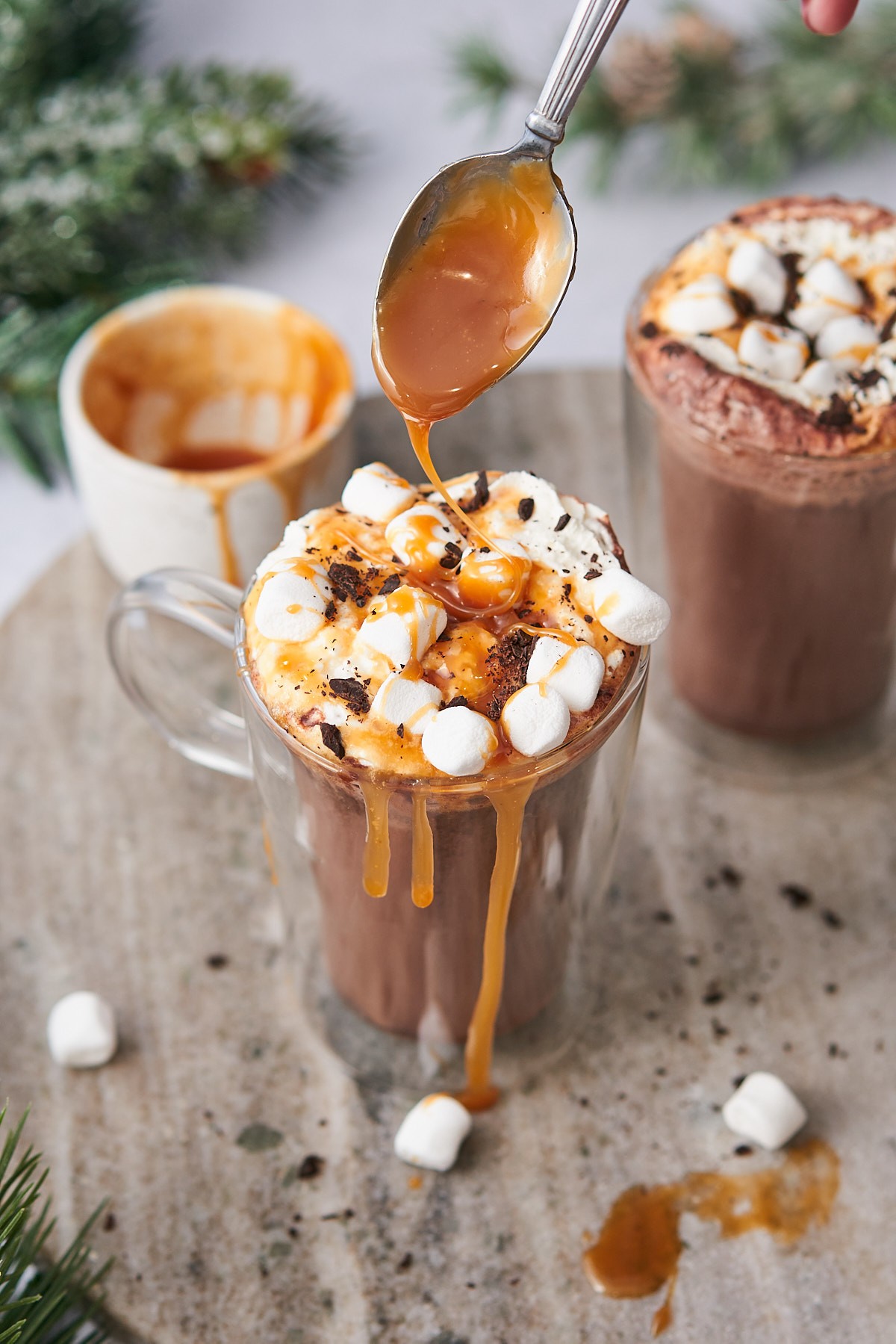 Decadent salted caramel hot chocolate with whipped cream and caramel drizzle, cozy setting, human hands holding mug