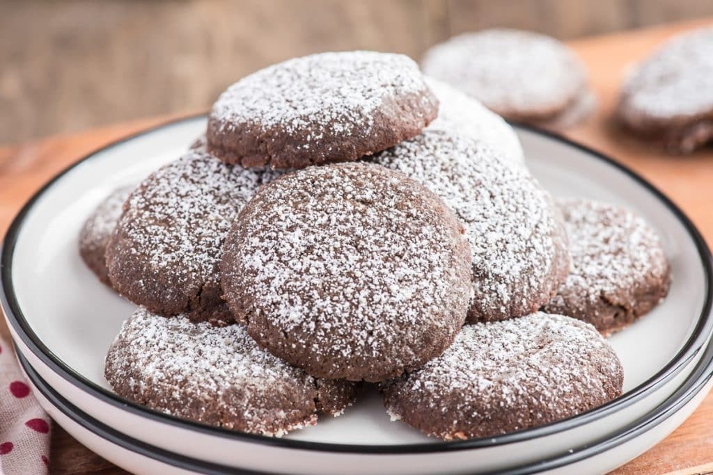 plate of dark cocoa sugar cookies with powdered sugar dusting, cozy kitchen scene