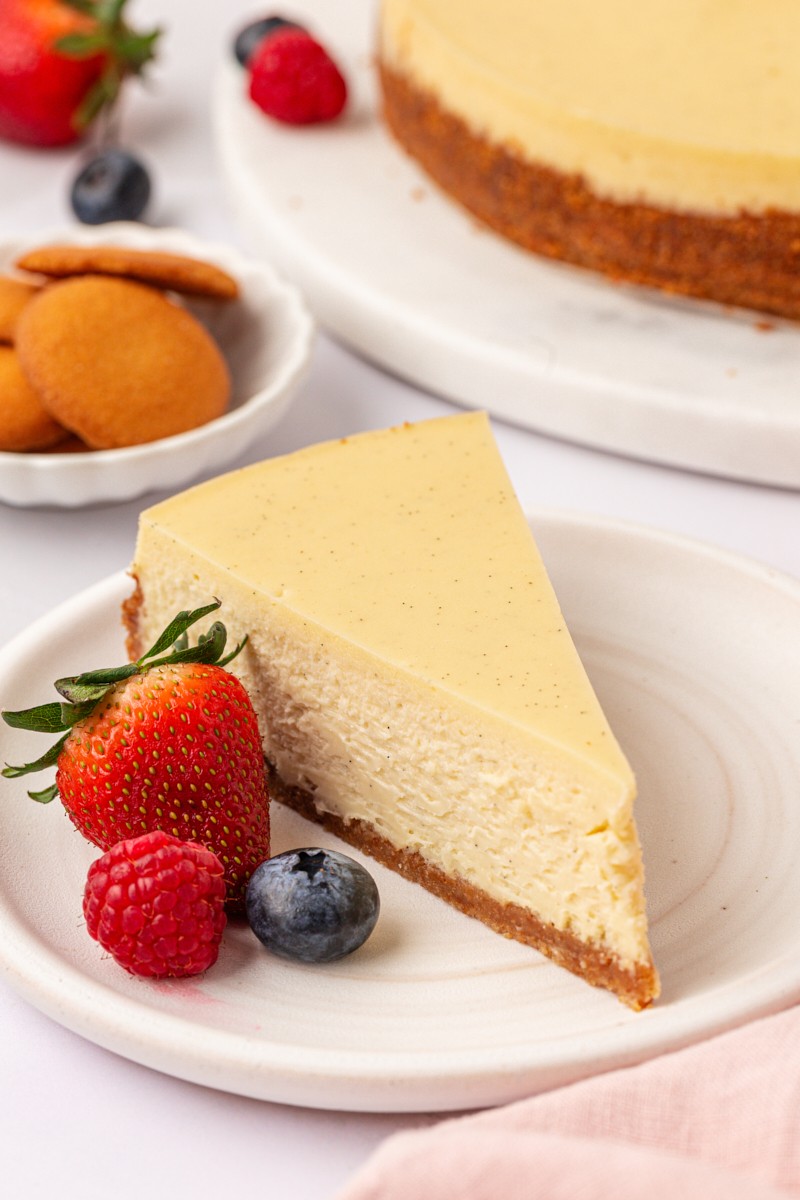 Decadent slice of vanilla bean cheesecake with a silky texture on a white plate, close-up