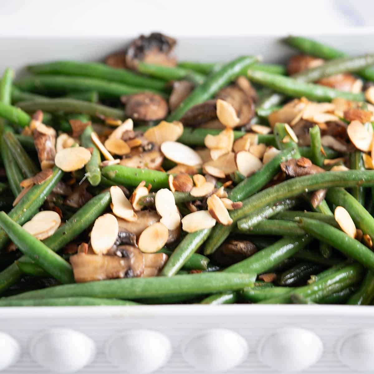 Gourmet toasted almond green bean casserole on a rustic holiday table, close-up, golden brown, vibrant green beans