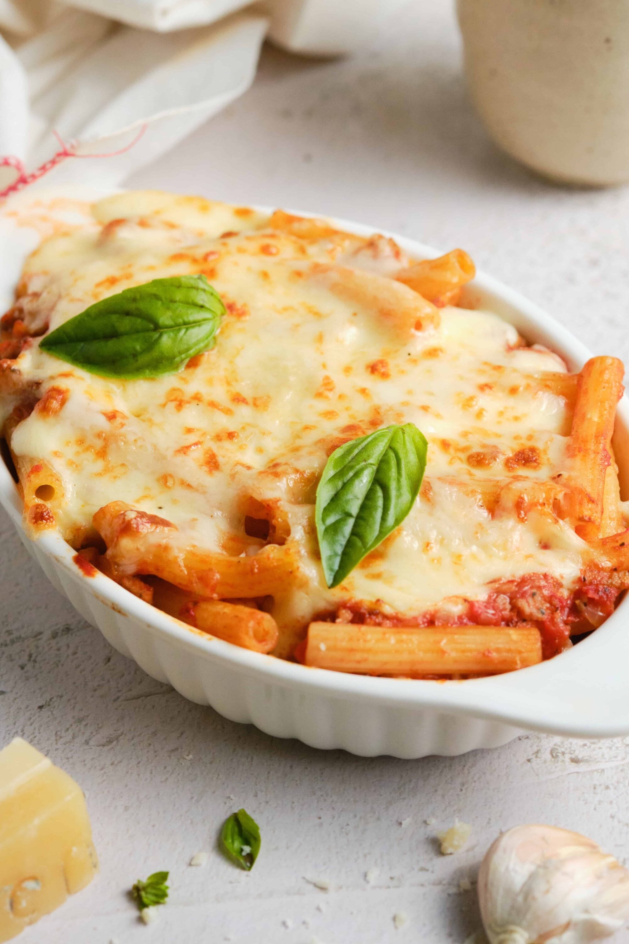 A bubbling casserole dish of cheesy baked ziti, garnished with fresh basil