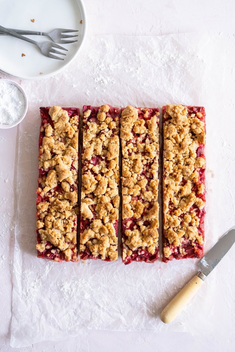 Hazelnut rhubarb chocolate bars on a wooden surface, styled with fresh rhubarb and hazelnuts