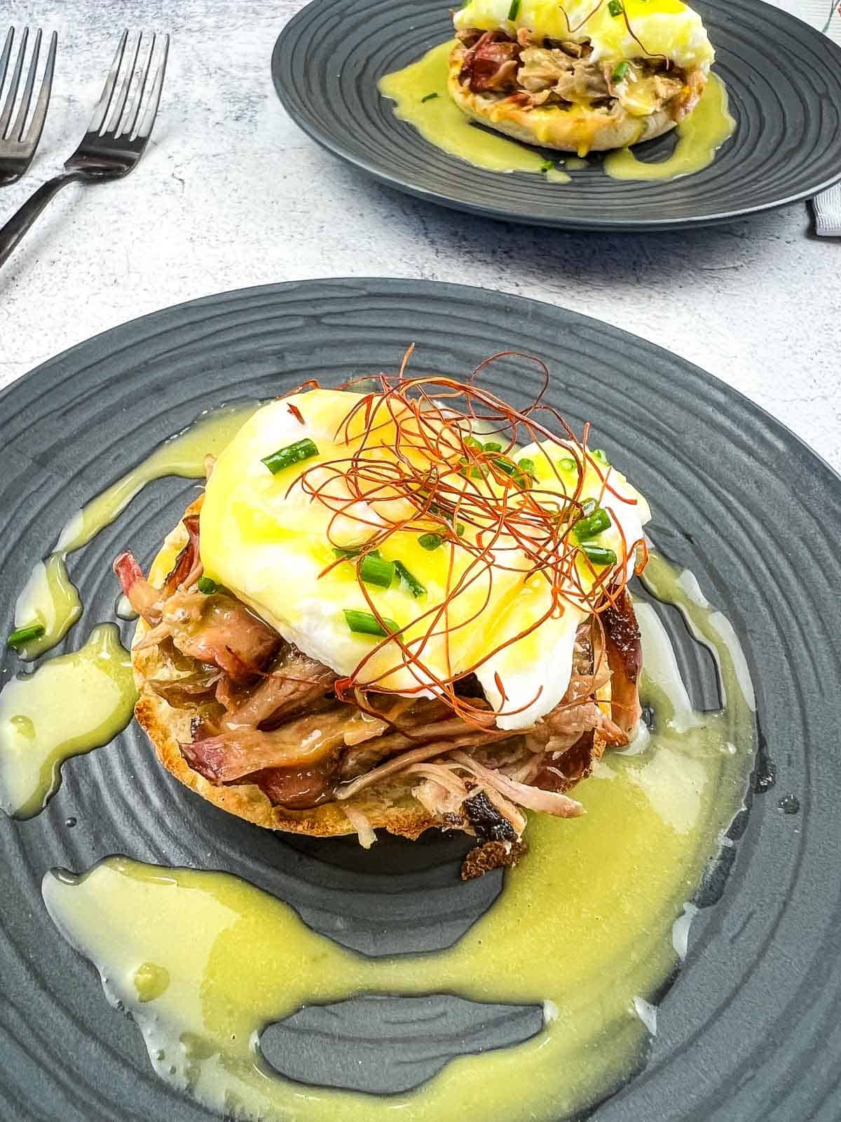pork chops with eggs benedict on a plate, hollandaise sauce drizzled