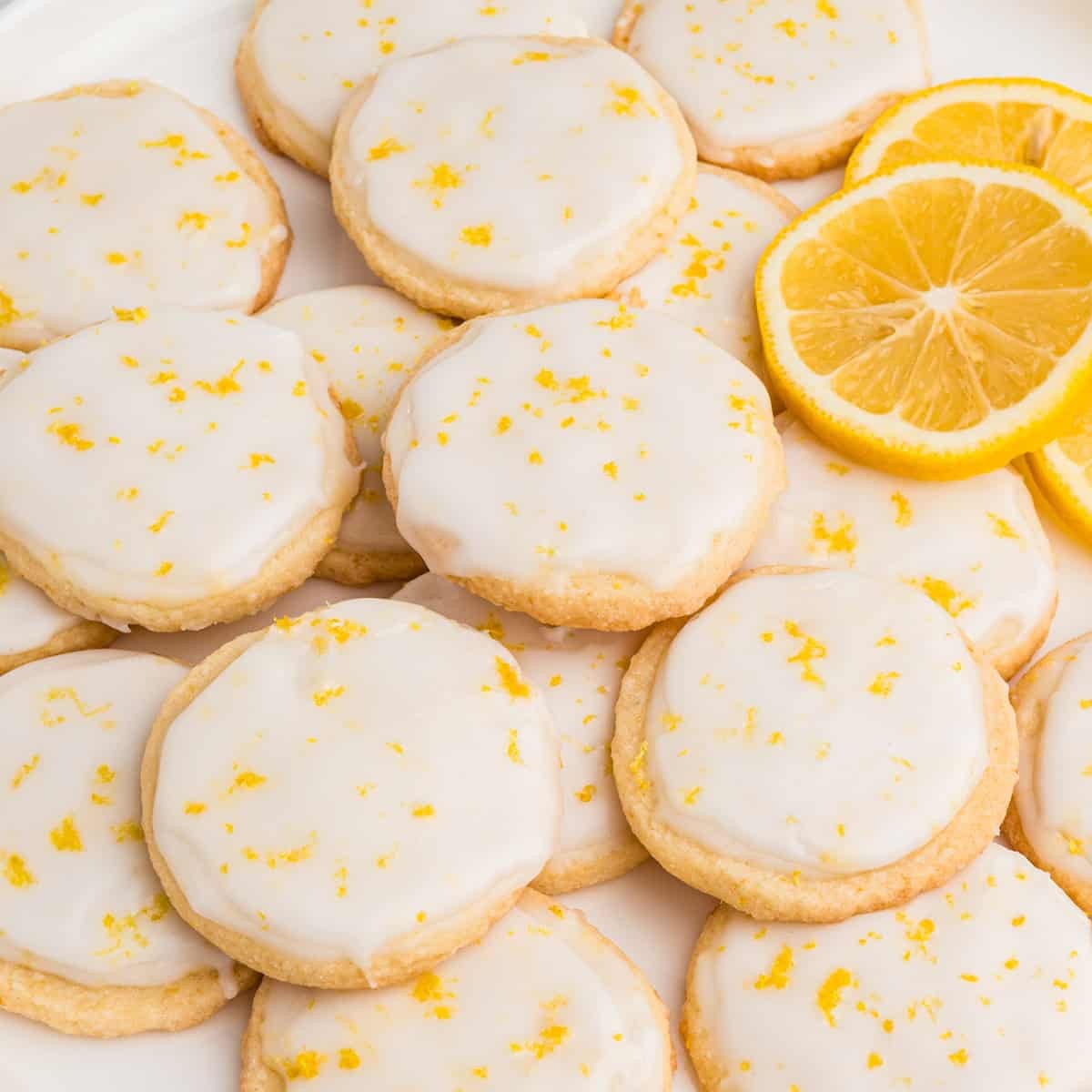 plate of bright lemon glazed sugar cookies with fresh lemon slices, inviting and delicious