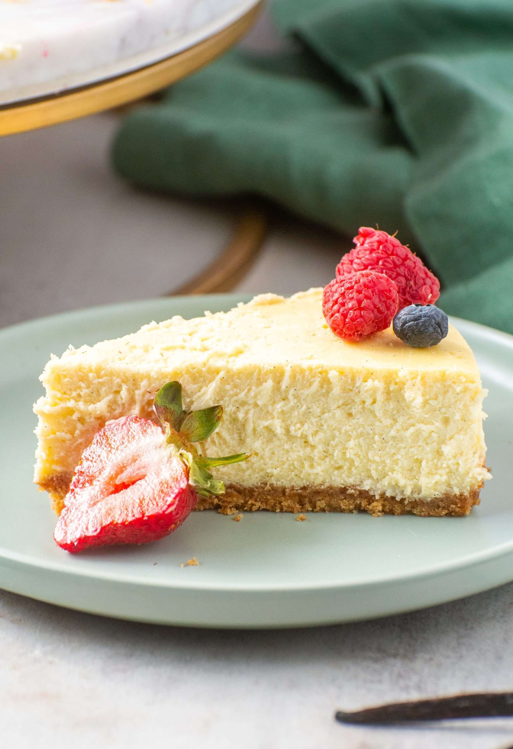slice of vanilla bean cheesecake with fresh berries on a white plate, creamy texture