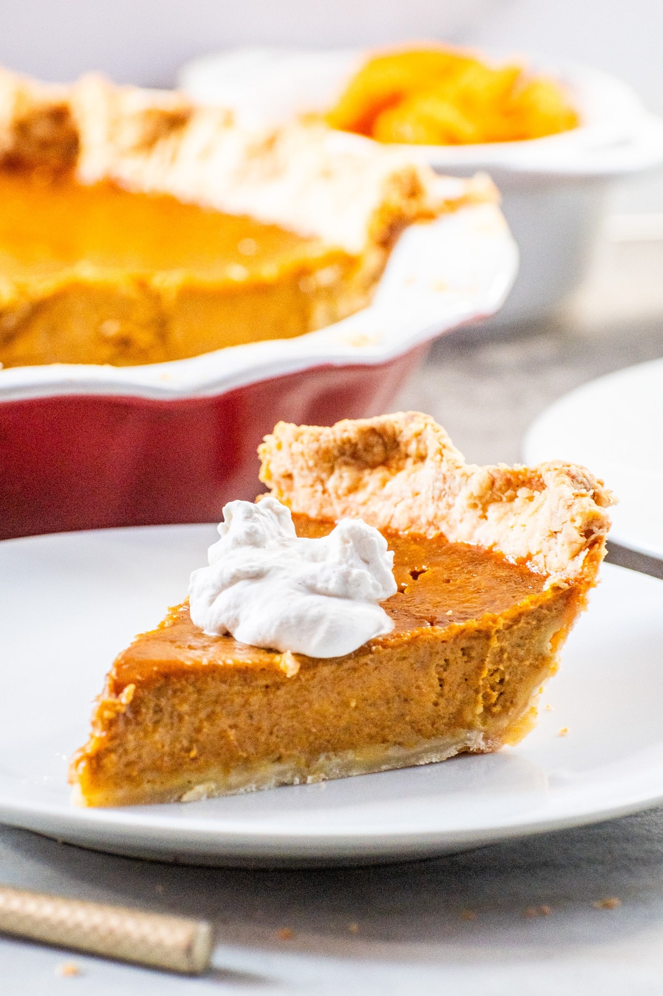Delicious creamy pumpkin pie slice with flaky butter crust and whipped cream