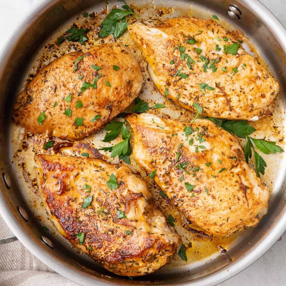 close up of perfectly pan seared juicy garlic chicken breast with herbs
