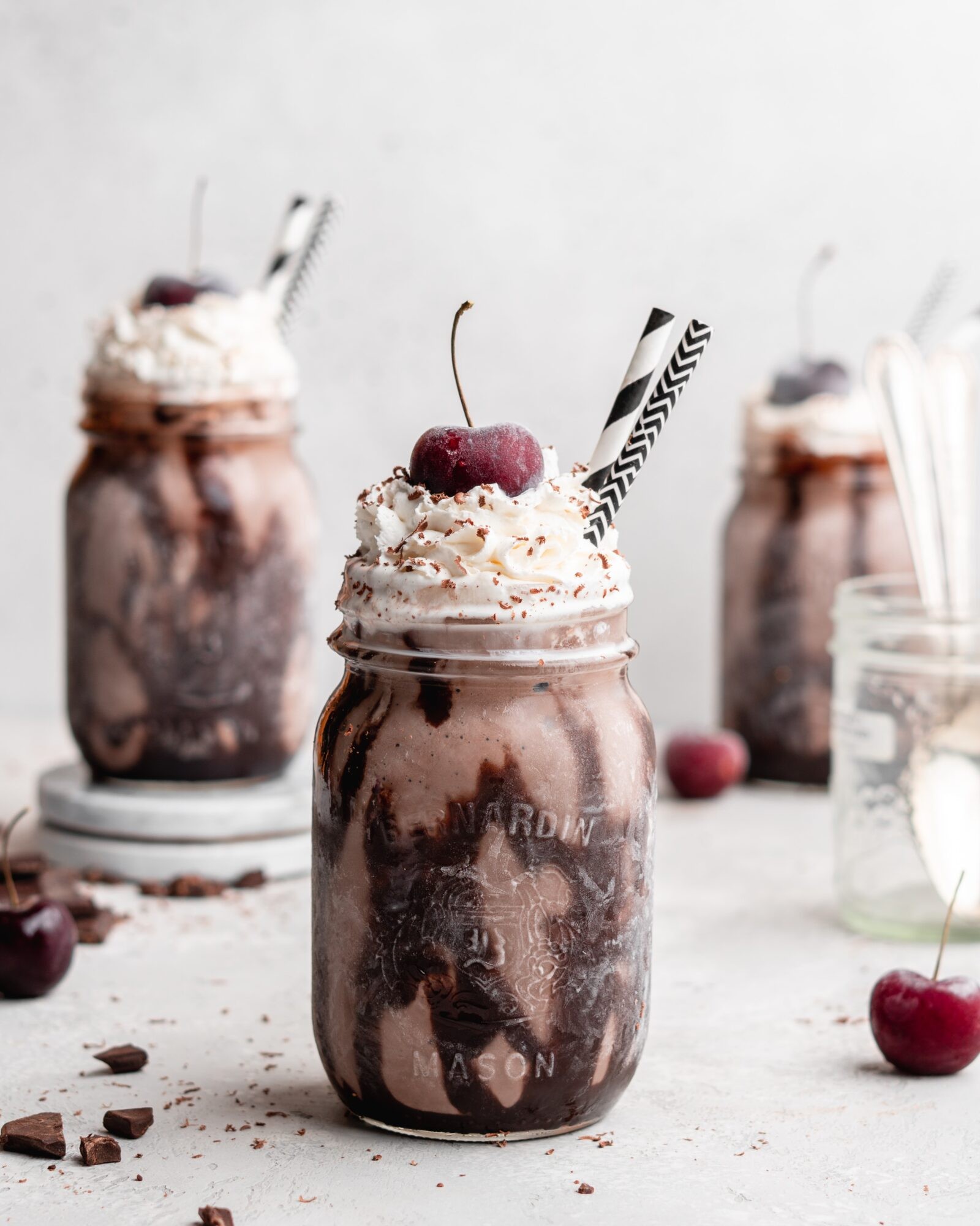 dark chocolate cherry lassi in a glass with fresh cherries and chocolate shavings