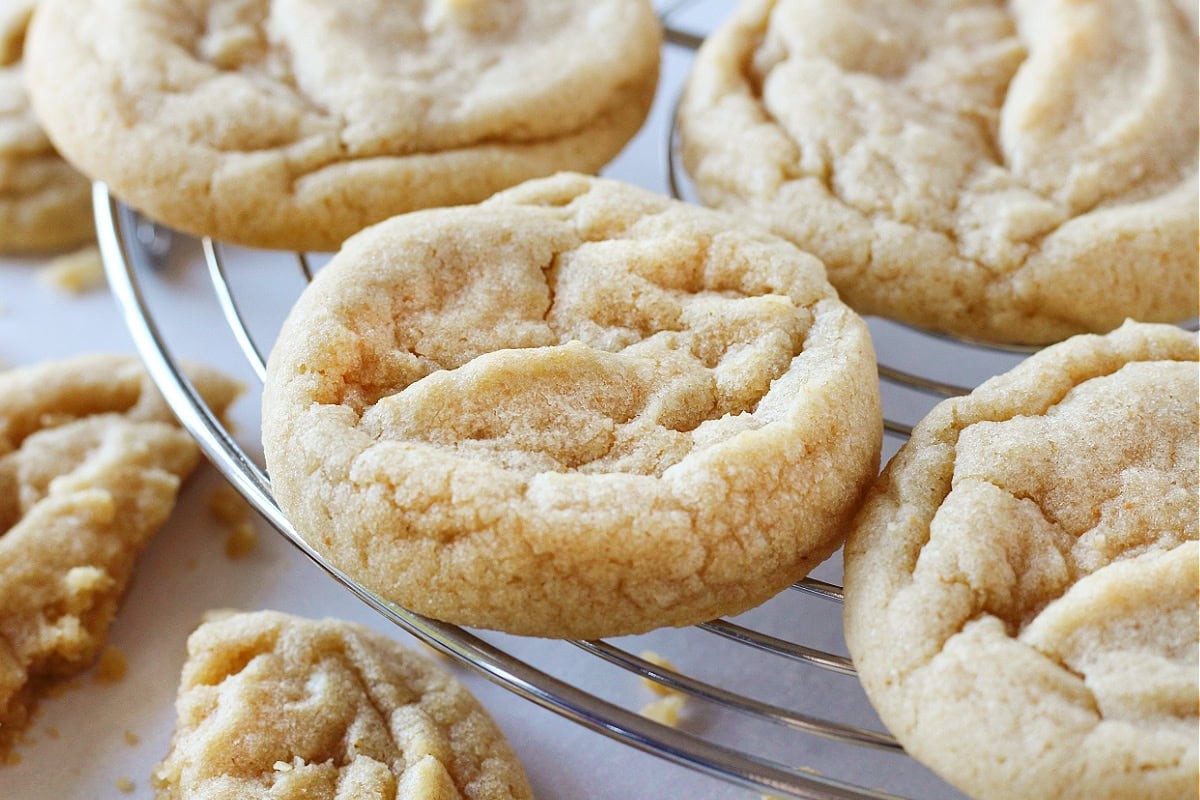 close-up shot of golden brown butter cookies on a cooling rack, some with slight crinkles, warm and inviting light