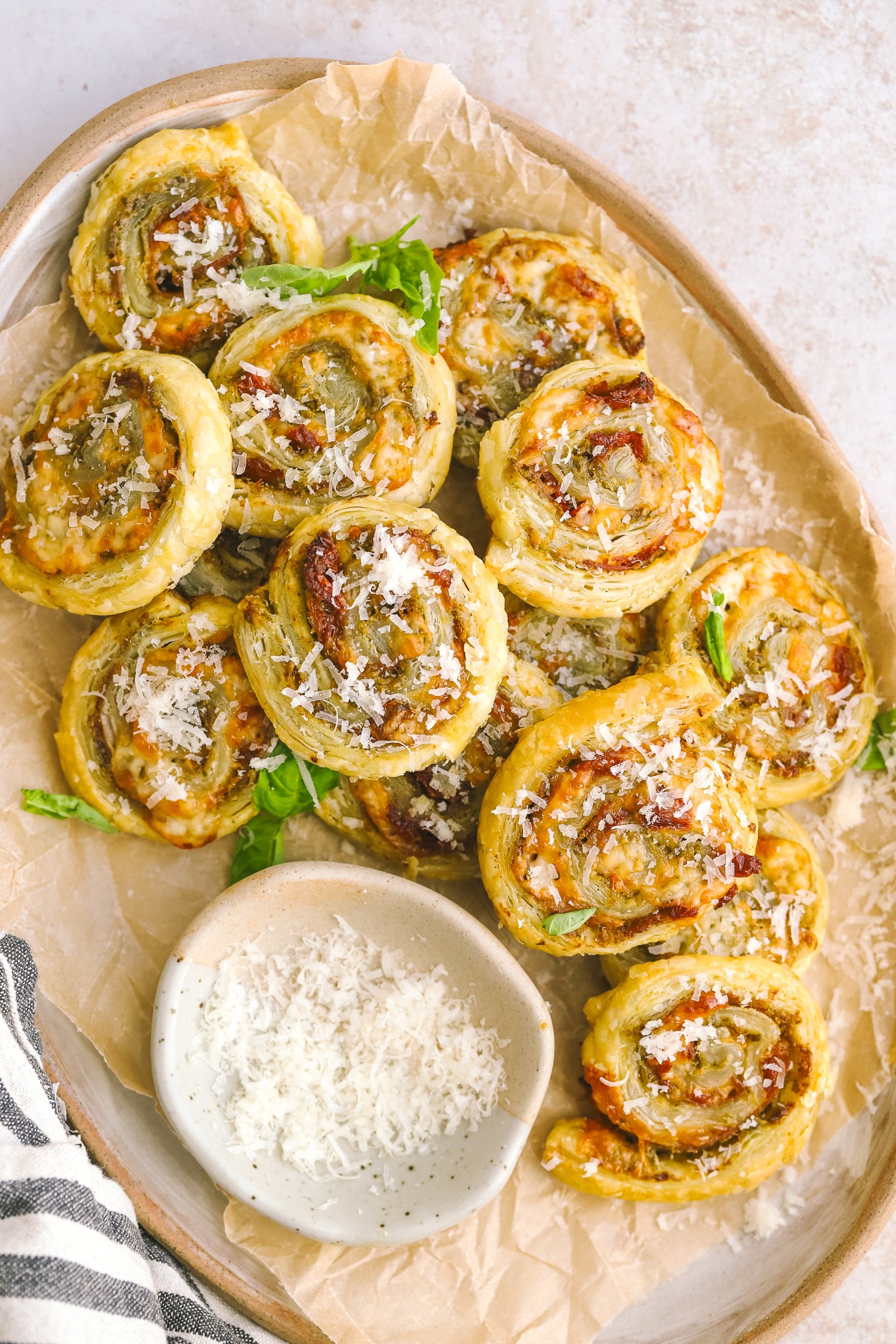 Golden brown pesto puff pastry pinwheels on a baking sheet with parchment paper